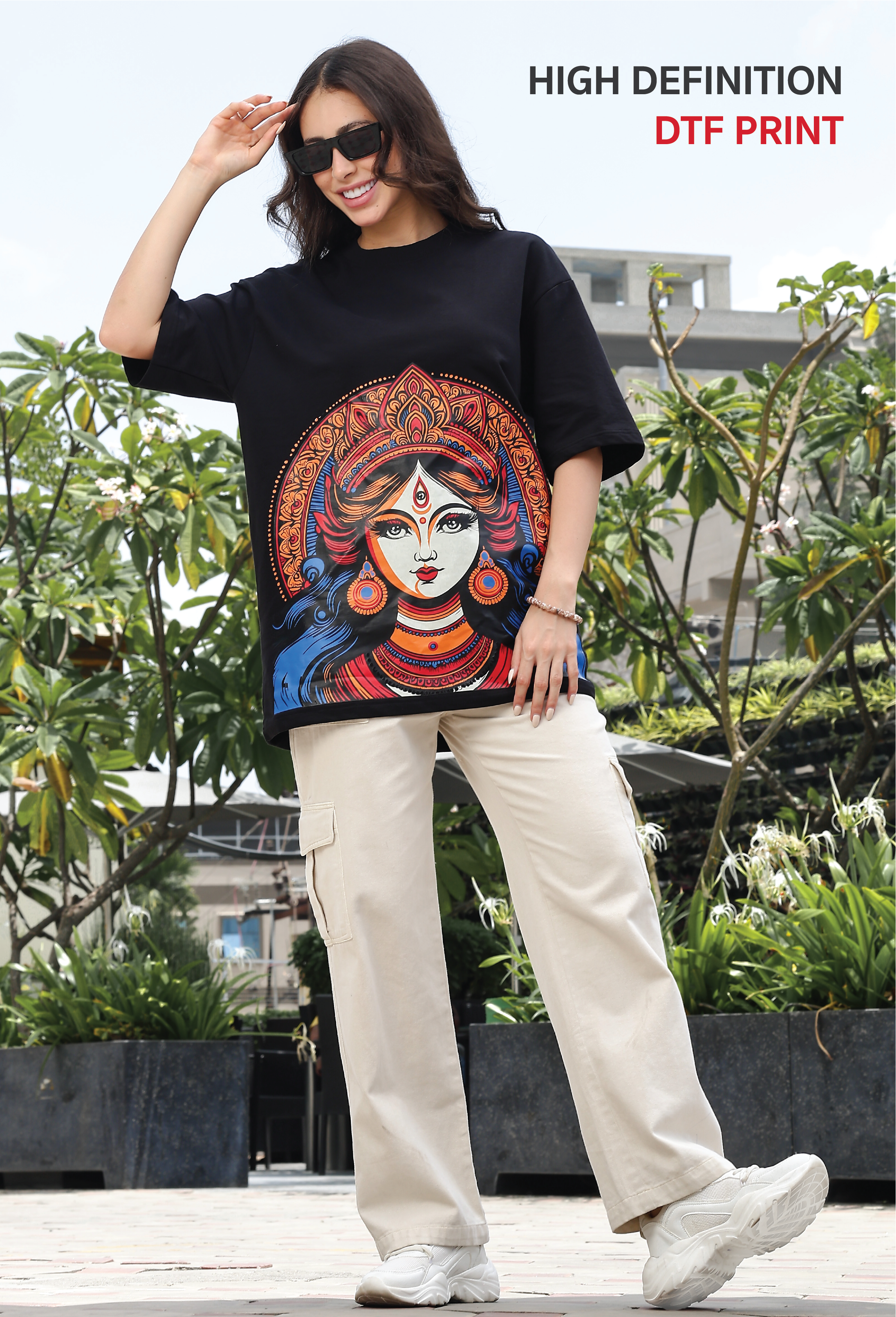 Woman wearing a black t-shirt with a colorful graphic design outdoors.